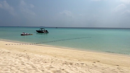 Speedboat and jet ski anchored in a calm turquoise lagoon near the beach