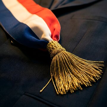 Detail of French mayor tricolor sash with gold tassels on dark blue suit during ceremony