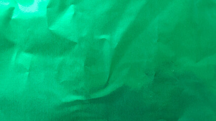 Glossy green origami paper background with subtle surface reflection and organic paper wrinkles