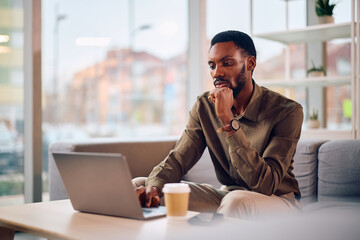 Pensive black businessman working on laptop in office.
