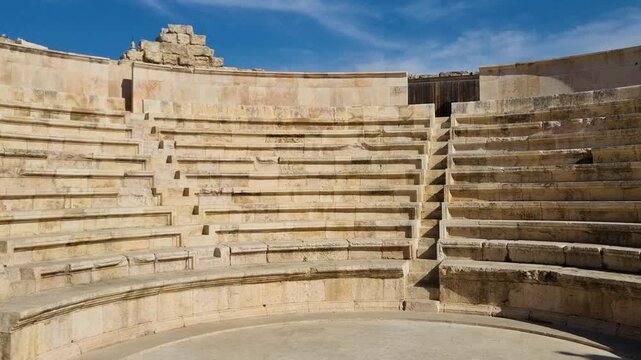 Clear daylight view inside the Roman Odeon Theater in Amman, Jordan, showing ancient stone seating and preserved historical architecture beneath a bright blue sky
