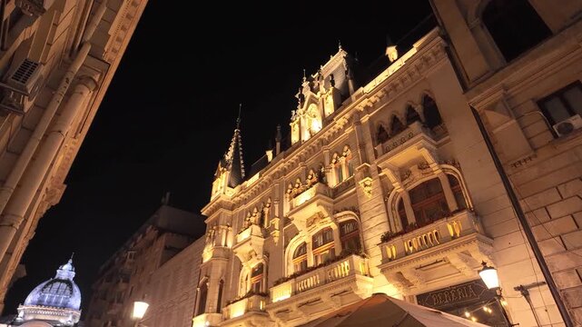 Ornate Gothic Revival architecture of Caru' cu Bere building illuminated at night in Bucharest