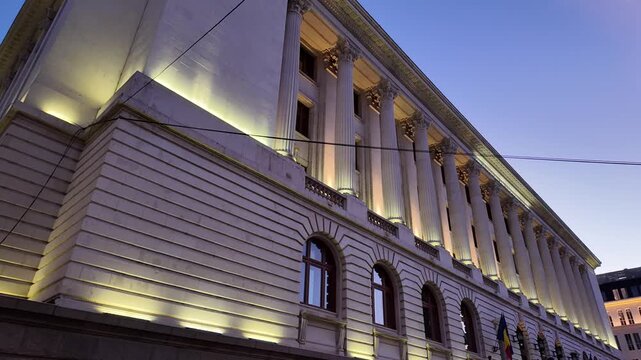 National Bank of Romania building displaying neoclassical architecture and columns illuminated at night