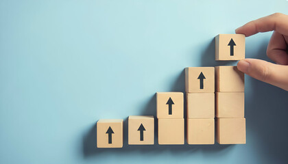 Hand placing wooden block with upward arrow on stack symbolizing business growth, success, and progress against light blue background