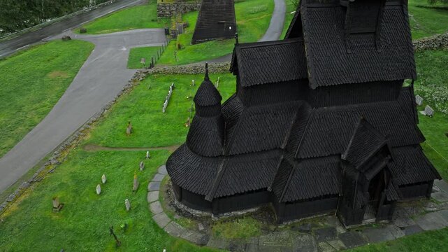 Close aerial view of Borgund Stave Church wooden exterior, Norway. Detailed medieval craftsmanship contrasts with bright green grass below.