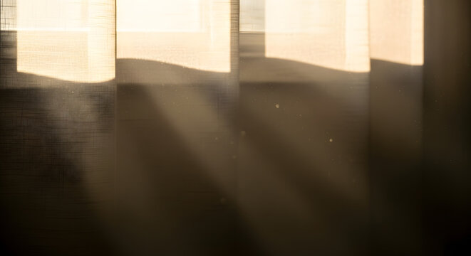 Dramatic light rays piercing through fabric window curtains in a dark room with visible dust particles floating in the air