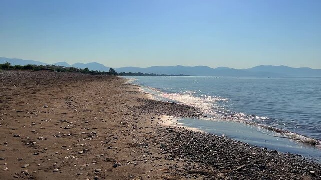Long sandy beach in sunny weather, located in the center of Finike. Beach on the Mediterranean coast and the coastal city of Finike in Turkey on a sunny summer day. 4K