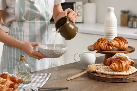 Baker with milk making delicious croissants in kitchen