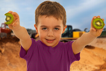 A young boy is holding two kiwis in his hands