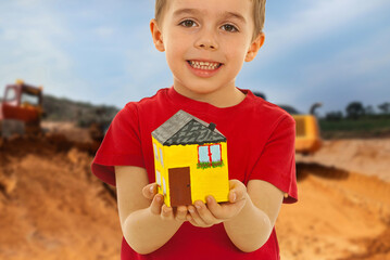 A young boy is holding a yellow house in his hands