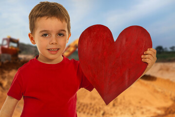 A young boy is holding a red heart in his hand
