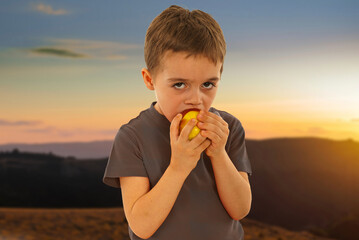 A boy is eating a yellow apple
