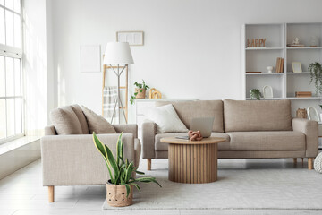 Interior of stylish living room with grey sofas, laptop on coffee table and big window
