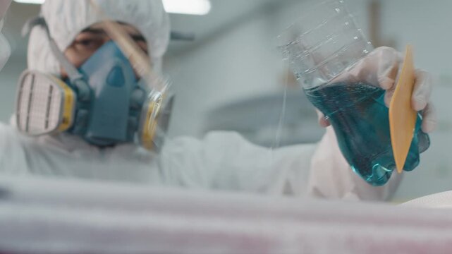 Surf board factory. Adult male shaper creates the surfing board on the factory and does glassing
