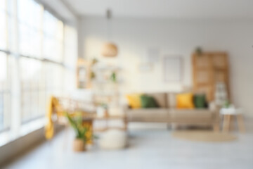Blurred view of stylish living room with grey sofa, chairs, coffee table and big window
