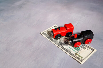 Model wooden train on bank bills with natural sunlight for transport cost inflation, travel debt and social mobility crisis themes. © Shutterly