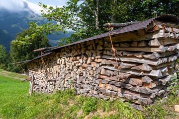 Stacked firewood pile with metal roof in Swiss Alps