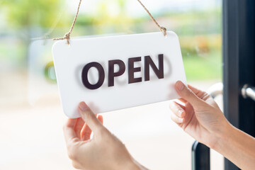 Turns the sign from closed to open welcoming customers to a new cafe and small business restaurant in the morning. New business coffee shop cafe. Happy Owner or waitress in apron