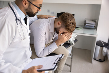 Delivering bad news with care. Empathetic caring young doctor soothe comfort male patient hiding face in palms after receiving critical diagnosis providing emotional support encouragement. Copy space