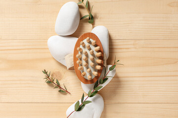 Composition with bottle of cosmetic product, massage brush, spa stones and eucalyptus branches on...
