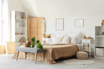 Interior of light bedroom with cozy bed and books on bedside bench