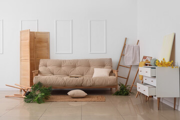 Obraz premium Interior of messy living room with white sofa and overturned furniture after earthquake