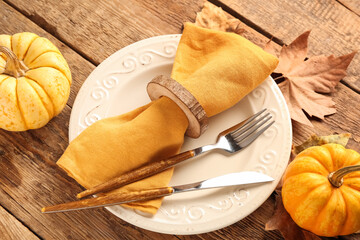 Beautiful table setting with fresh pumpkins and autumn leaves on wooden background