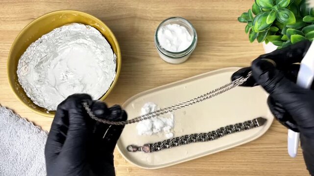 An eco-friendly way to clean silver jewelry using baking soda. Wearing black gloves, clean silver jewelry from tarnish.
