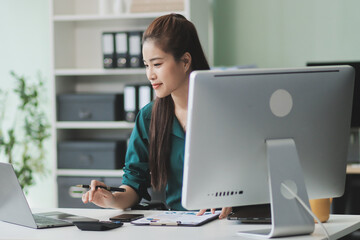 Determined asian businesswoman works late in a modern office, confidently analyzing data on her laptop, embodying success and professionalism with a smile