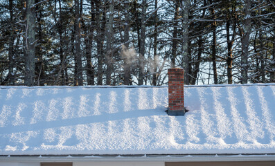 smoke coming from chimney on snow covered roof