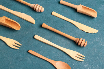 Different wooden kitchen utensils on green background