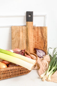 Wicker basket with different kinds of onion on light background