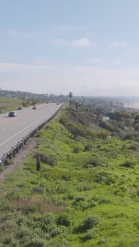 Vertical aerial footage revealing a Malibu California highway sign along Highway 1 with ocean coastline in the background and smooth forward cinematic motion