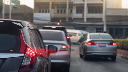 Driving of cars on the asphalt road with turn on brake ligt. Ready to park and queue on the street. Stop by traffic red light control in the city at morning time.