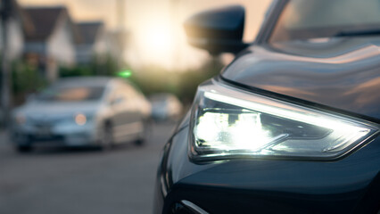 Detail Shot of modern car front LED headlight. Luxury automobile exterior part with reflection. Transportation and vehicle technology on the road inside the village.