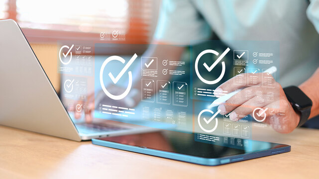 Businessman using digital tablet and laptop with virtual checklist and checkmark icons. Concept of approval process, task management, workflow, and digital verification system.