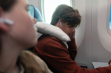 Obraz premium Young travelers sit on an airplane while listening to music