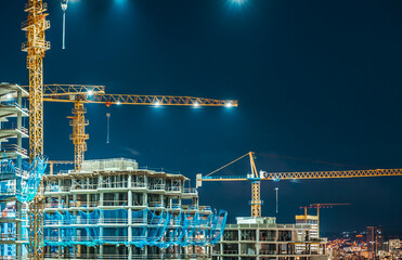 Construction Site at Night with Illuminated Tower Cranes and Building Skeletons