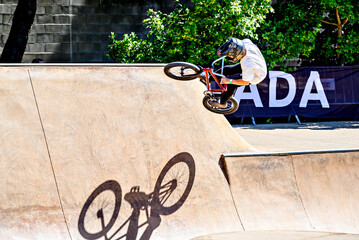 Obraz premium A young man practicing BMX and performing tricks at the skatepark.