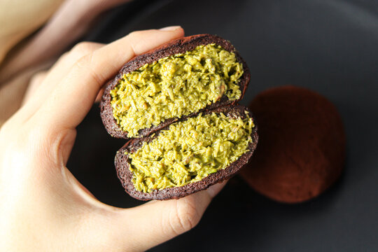 A hand holding the Dubai Chewy Cookie with the chewy outer layer opened to reveal the filling of pistachio and kataifi.