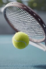 Close up action shot of a yellow tennis ball making contact with a tennis racket on a blue court