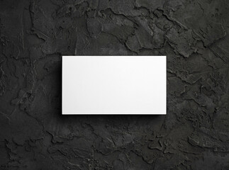 Blank white business card on black textured surface. Template for graphic designers portfolios. Flat lay.