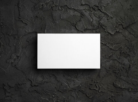 Blank white business card on black textured surface. Template for graphic designers portfolios. Flat lay.