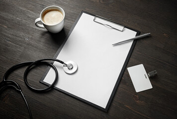 Health care concept. Blank clipboard, stethoscope, badge, pen and coffee cup on wooden surface.