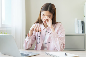 Eye problem concept, fatigue asian young woman tired eyes, irritated rubbing nose, relief vision pain after work on laptop computer, eye strain, hand holding glasses, suffer migraine, bad blurry.