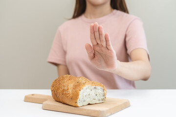 Gluten allergy, asian young woman hand push out, refusing to eat white bread loaf on board in...
