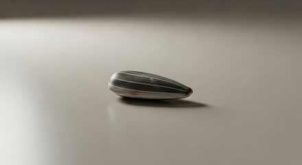 Metallic Bullet-Shaped Object Resting on a Smooth, Light Surface.