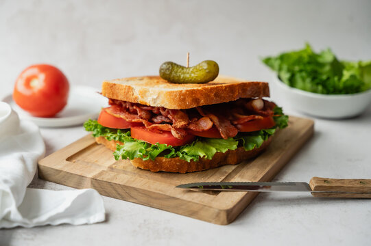 Close up of BLT sandwich on wooden board and white backdrop.