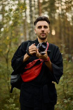 Person holds a camera in a forest during daytime