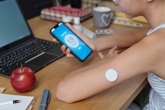 Person monitoring glucose level with mobile app while studying at desk